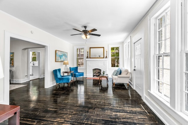 sitting room featuring dark wood-type flooring, a fireplace, and ceiling fan