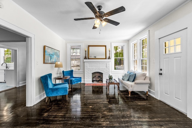 living area with a brick fireplace, wood-type flooring, and ceiling fan