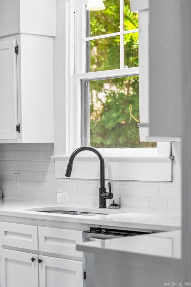 interior details with dishwasher, white cabinets, tasteful backsplash, and sink