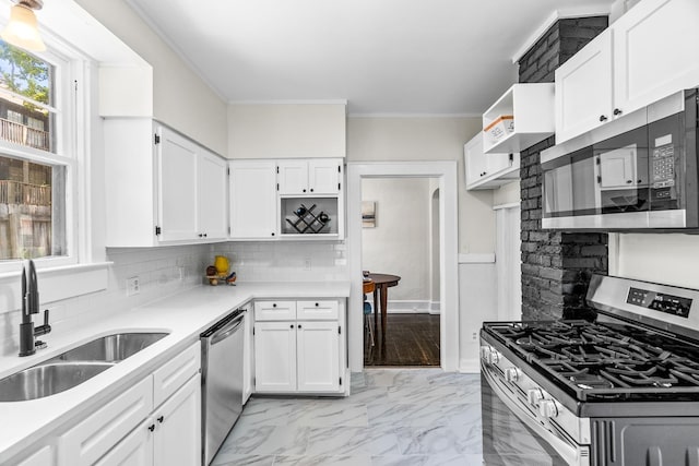 kitchen featuring appliances with stainless steel finishes, white cabinetry, decorative backsplash, sink, and ornamental molding