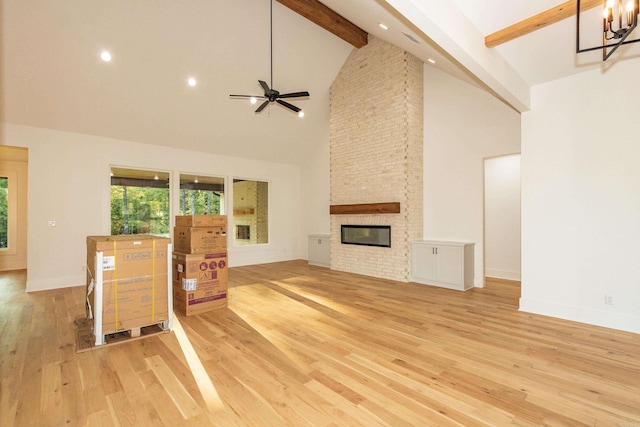 living room with a fireplace, beam ceiling, light hardwood / wood-style flooring, high vaulted ceiling, and ceiling fan with notable chandelier