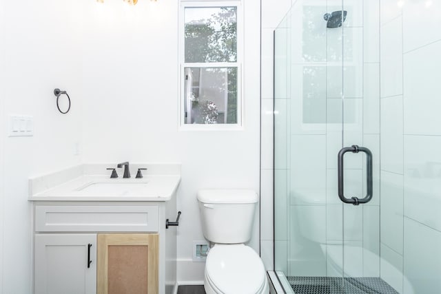 bathroom with a shower with shower door, toilet, and vanity