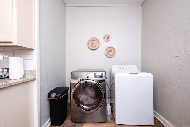 clothes washing area featuring dark hardwood / wood-style floors, cabinets, and washing machine and clothes dryer