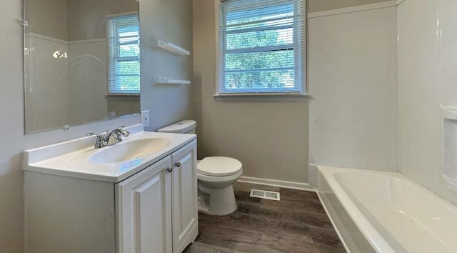 full bathroom with toilet, a wealth of natural light, hardwood / wood-style floors, and vanity