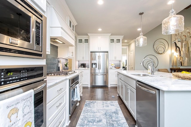 kitchen featuring custom range hood, white cabinetry, appliances with stainless steel finishes, and decorative backsplash