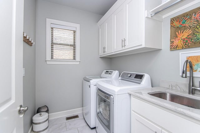 laundry room featuring sink, cabinets, and washer and clothes dryer