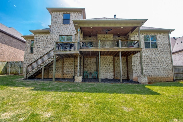 back of property with a wooden deck, a yard, and ceiling fan