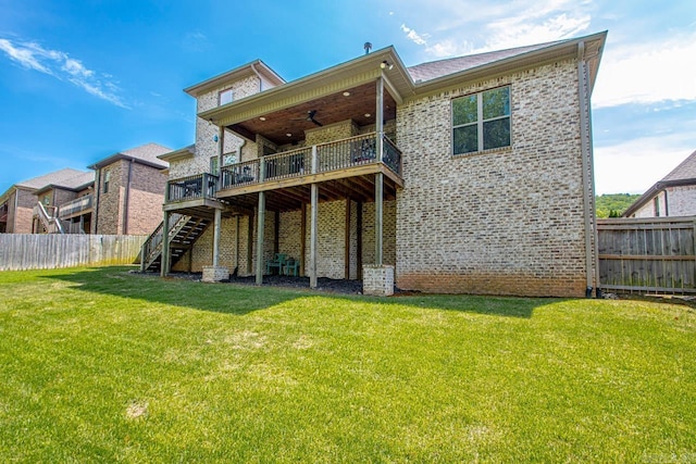 back of property featuring ceiling fan, a deck, and a lawn