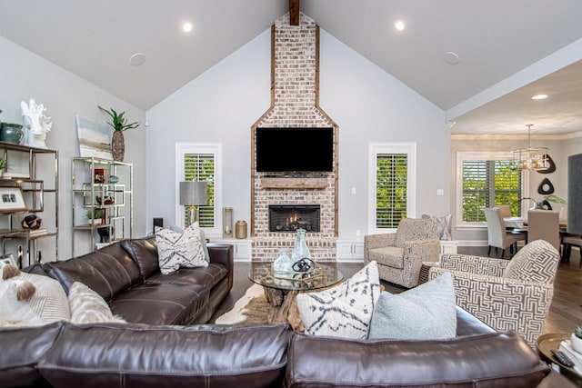 living room with hardwood / wood-style floors, an inviting chandelier, lofted ceiling with beams, and a brick fireplace