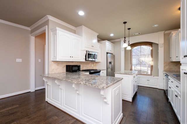 kitchen featuring pendant lighting, appliances with stainless steel finishes, white cabinets, light stone countertops, and a kitchen island