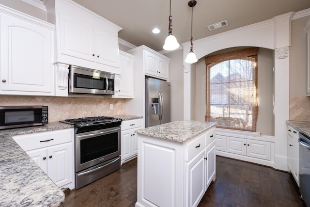 kitchen featuring a kitchen island, white cabinetry, hanging light fixtures, and stainless steel appliances