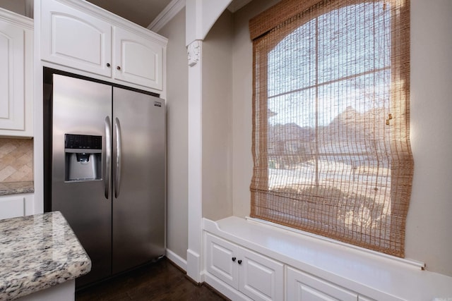 kitchen with white cabinets, backsplash, stainless steel fridge, light stone counters, and crown molding