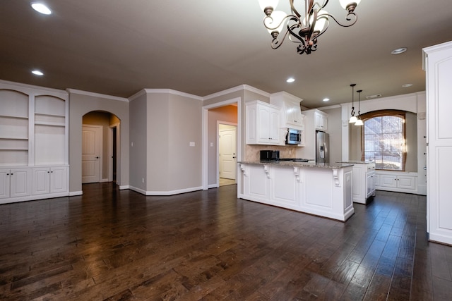 kitchen featuring hanging light fixtures, appliances with stainless steel finishes, white cabinetry, a center island, and dark hardwood / wood-style floors