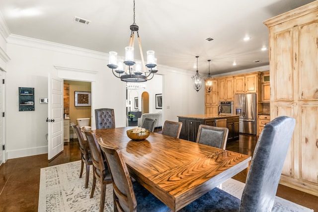 dining space with dark tile patterned floors, ornamental molding, and an inviting chandelier