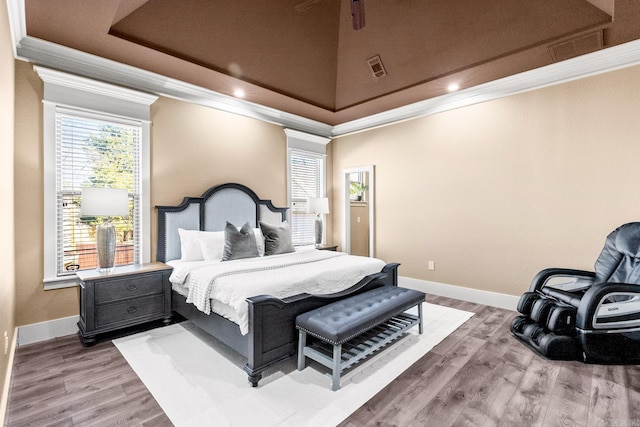 bedroom with light wood-type flooring, a high ceiling, and ornamental molding