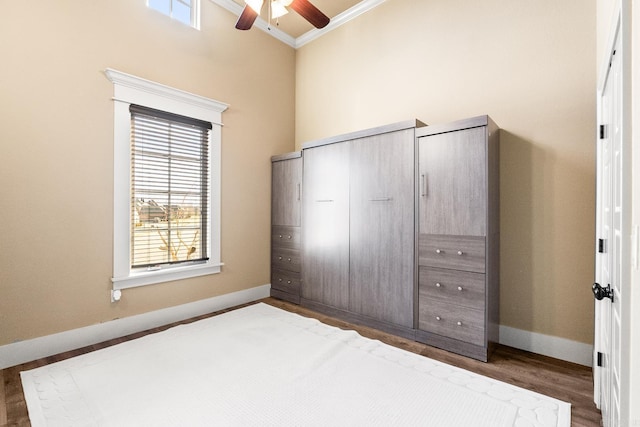 unfurnished bedroom featuring ceiling fan, crown molding, and dark wood-type flooring