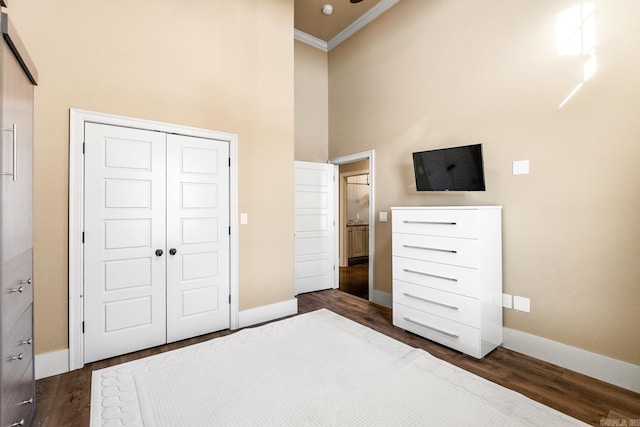 unfurnished bedroom featuring crown molding, dark hardwood / wood-style floors, a closet, and a high ceiling