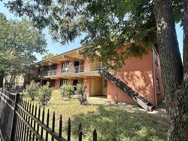 rear view of property featuring a balcony and a yard