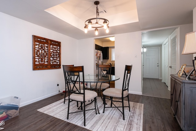 dining area featuring dark wood-type flooring and a tray ceiling