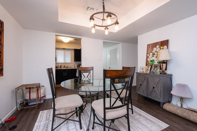 dining room featuring sink, dark hardwood / wood-style flooring, and a tray ceiling