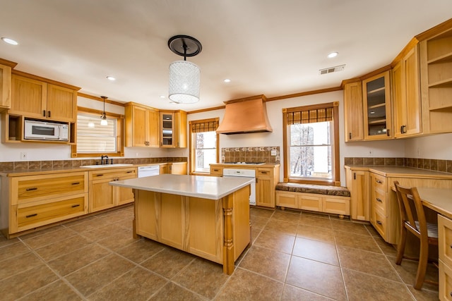 kitchen featuring white appliances, sink, premium range hood, hanging light fixtures, and crown molding