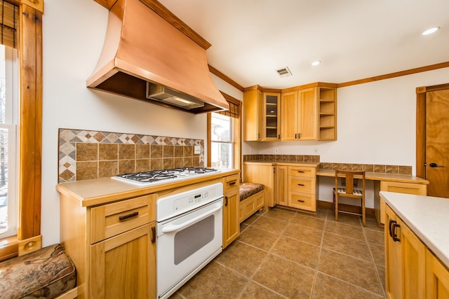 kitchen with premium range hood, white appliances, crown molding, and built in desk