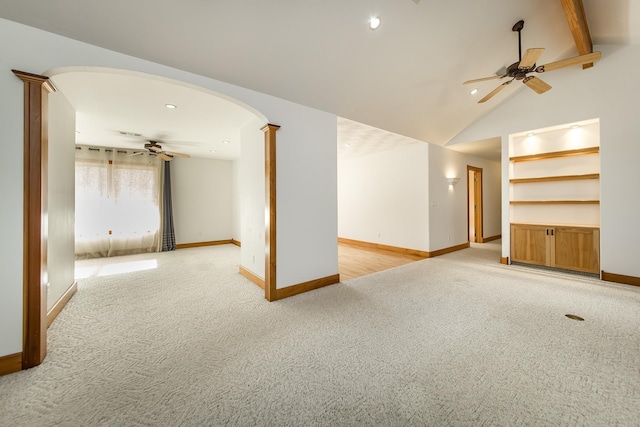 spare room with ceiling fan, decorative columns, light carpet, and vaulted ceiling with beams