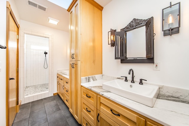 bathroom with tiled shower and vanity