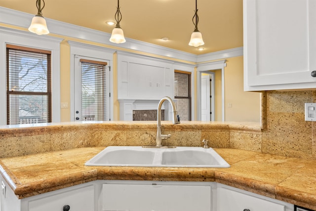 kitchen with white cabinets, tasteful backsplash, sink, hanging light fixtures, and ornamental molding