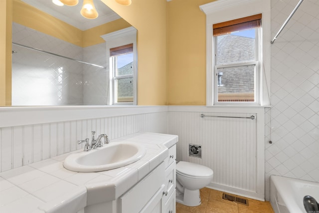 full bathroom with tiled shower / bath combo, tile patterned floors, vanity, toilet, and crown molding