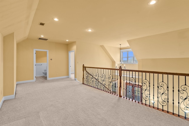 hallway featuring light carpet, an inviting chandelier, and vaulted ceiling