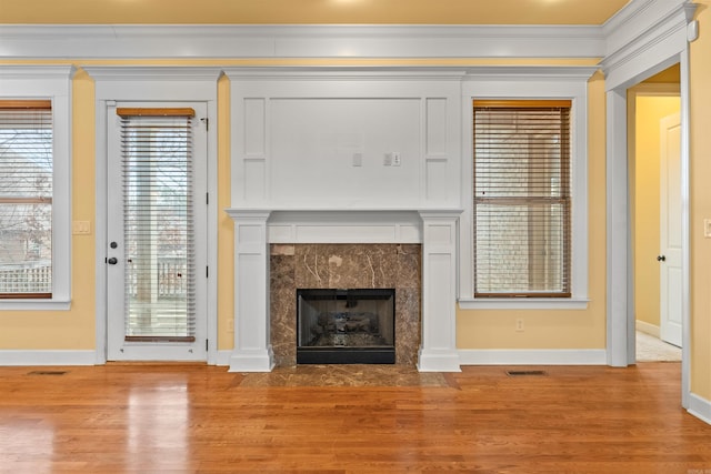 unfurnished living room with light hardwood / wood-style flooring, crown molding, and a premium fireplace