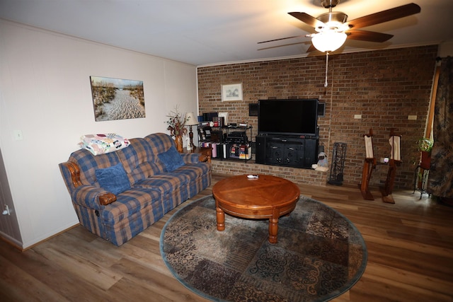 living room featuring hardwood / wood-style flooring, brick wall, and ceiling fan