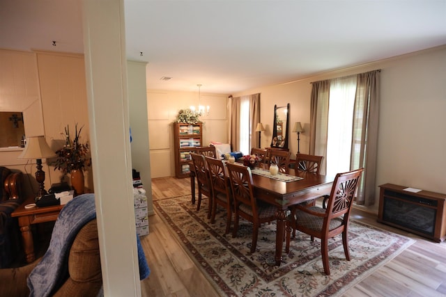 dining room with light wood-type flooring, crown molding, and a notable chandelier