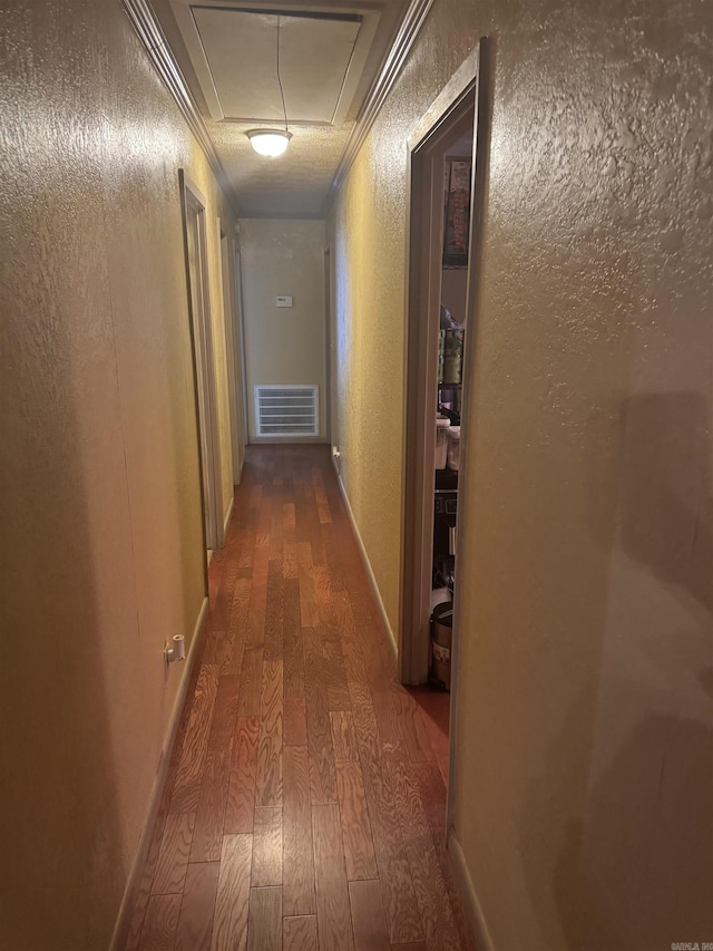 corridor with crown molding, dark hardwood / wood-style flooring, and a textured ceiling