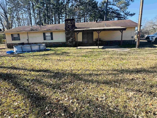 back of house featuring a covered pool, a patio area, and a lawn