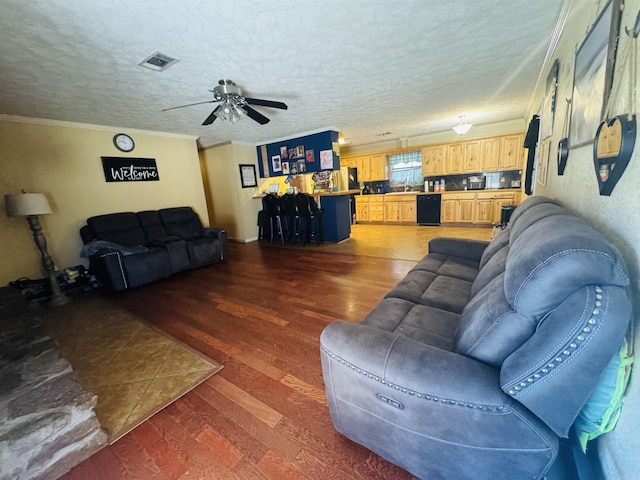 living room with crown molding, ceiling fan, dark hardwood / wood-style floors, and a textured ceiling