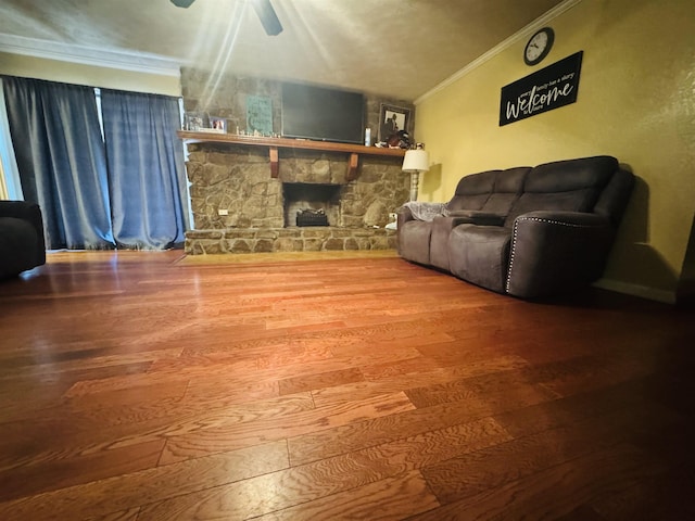 living room featuring ceiling fan, ornamental molding, a fireplace, and hardwood / wood-style floors