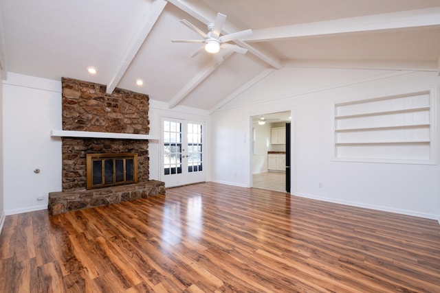 unfurnished living room with built in shelves, a stone fireplace, lofted ceiling with beams, and ceiling fan