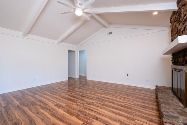 unfurnished living room featuring a stone fireplace, dark hardwood / wood-style floors, vaulted ceiling with beams, and ceiling fan