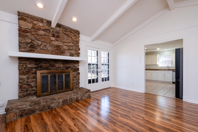 unfurnished living room with a fireplace, plenty of natural light, and vaulted ceiling with beams