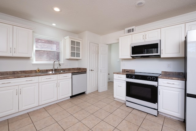 kitchen with white appliances, a textured ceiling, white cabinetry, sink, and light tile patterned flooring