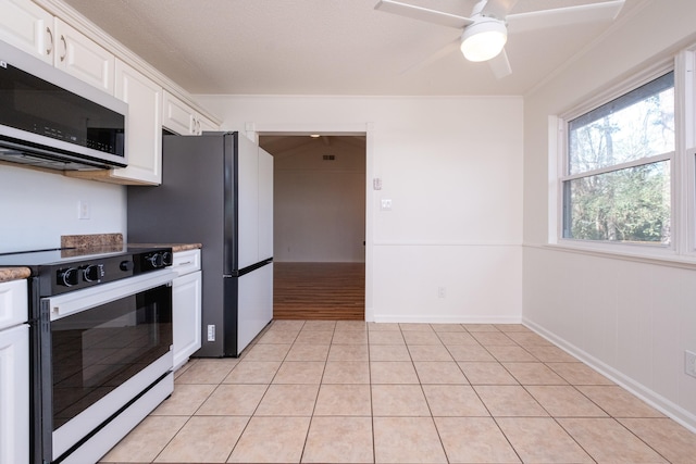 kitchen featuring light tile patterned floors, white cabinets, appliances with stainless steel finishes, and ceiling fan