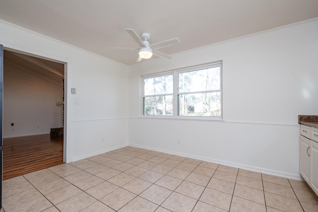 tiled empty room with ceiling fan, crown molding, and a textured ceiling