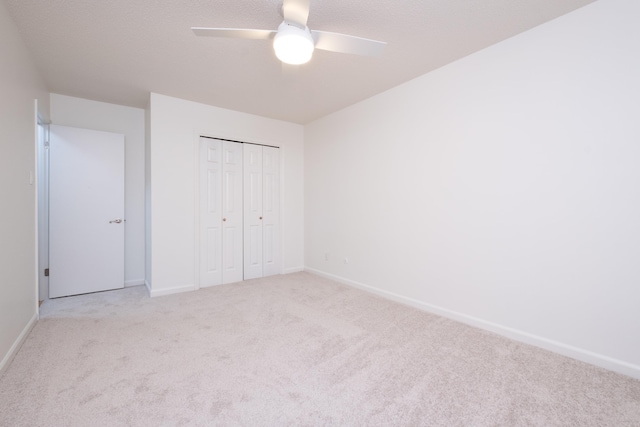 unfurnished bedroom featuring light carpet, a closet, and ceiling fan