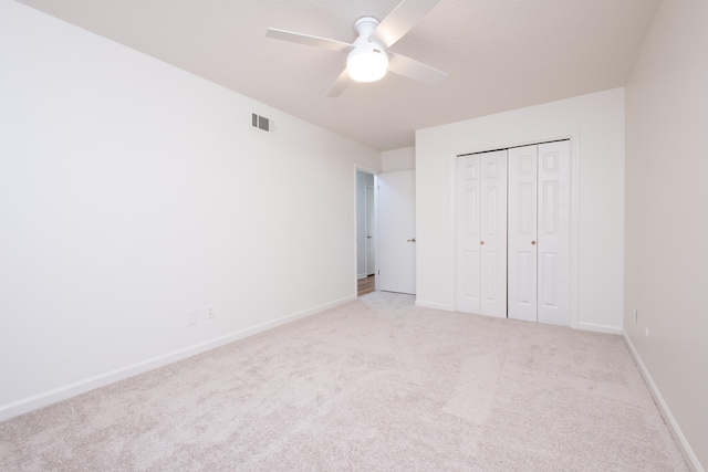 unfurnished bedroom featuring ceiling fan, a closet, and light carpet