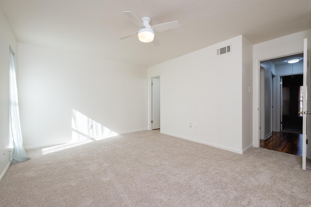 spare room with light carpet, a textured ceiling, and ceiling fan