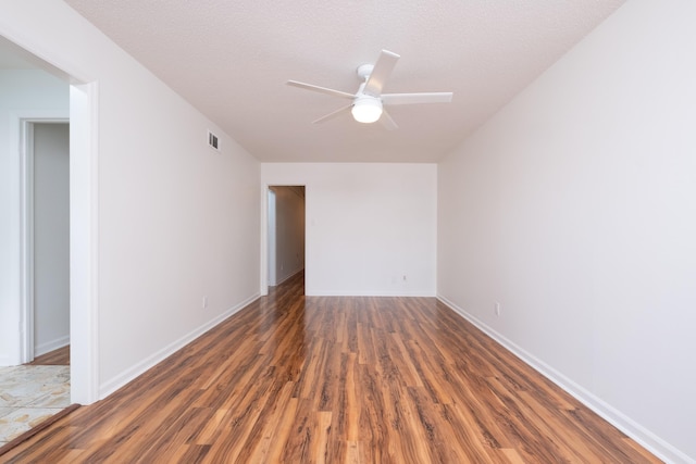 empty room with ceiling fan, dark wood-type flooring, and a textured ceiling