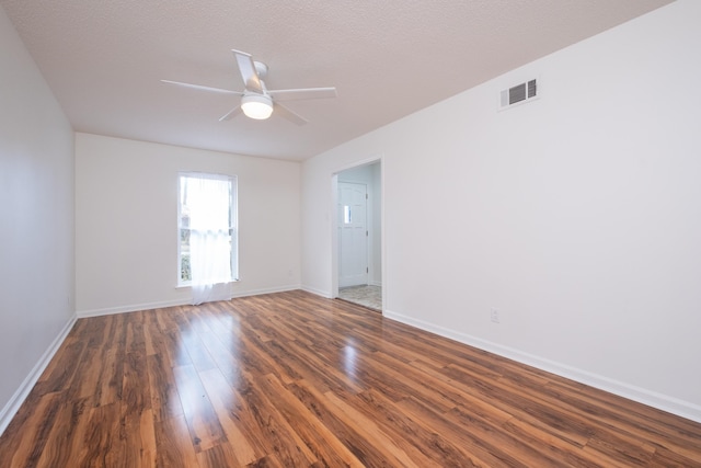 empty room featuring dark wood-type flooring, a textured ceiling, and ceiling fan