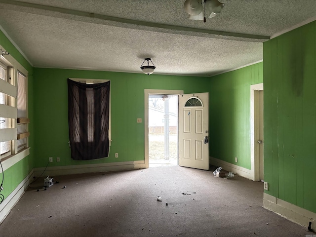 spare room featuring ornamental molding, carpet flooring, a textured ceiling, and baseboards